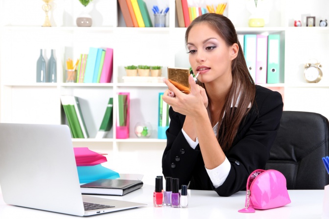 Eine Frau sitzt beim Schreibtisch und trägt Business Make-up auf