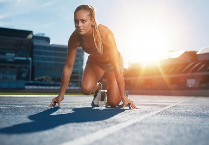 Eine Frau ist auf einer Laufbahn und bereitet sich auf einen Sprint vor