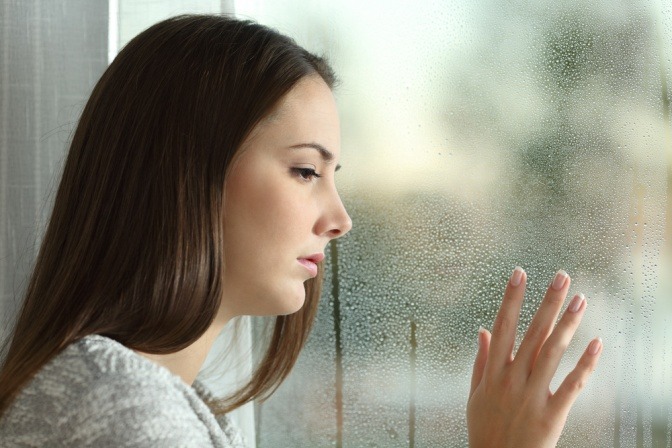 Traurige Frau an einer Fensterscheibe