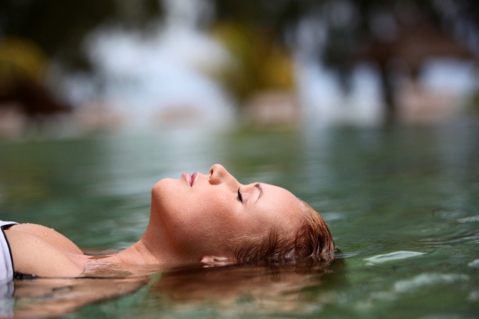 Eine Frau liegt bei einer Thalasso Behandlung mit dem Kopf im Wasser