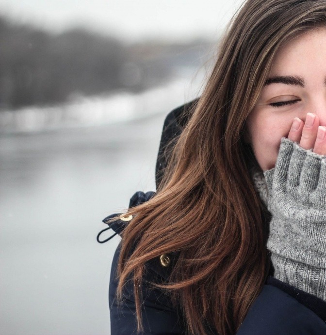 Eine Frau mit glatten Haaren trägt fingerlose Handschuhe und eine dicke Jacke