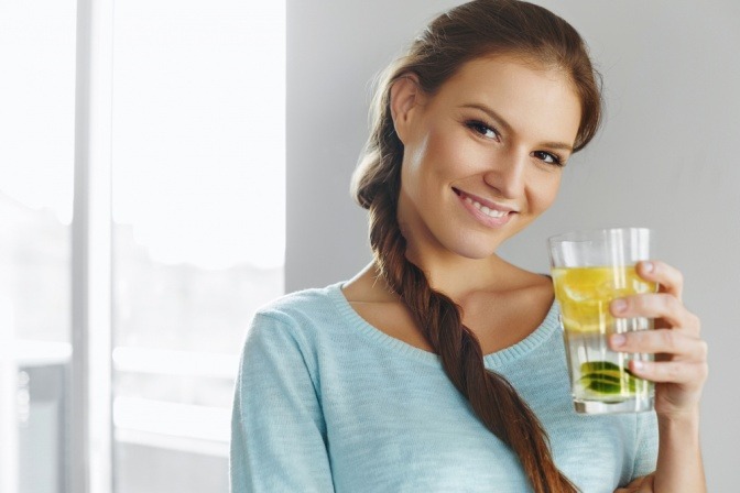 Eine Frau trinkt Wasser mit Zitronen