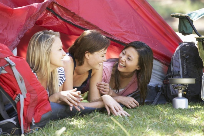 Drei Frauen liegen bei einem Frauencamp in einem Zelt