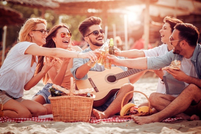 Eine Gruppe von Freunden feiert ausgelassen bei einem Picknick.