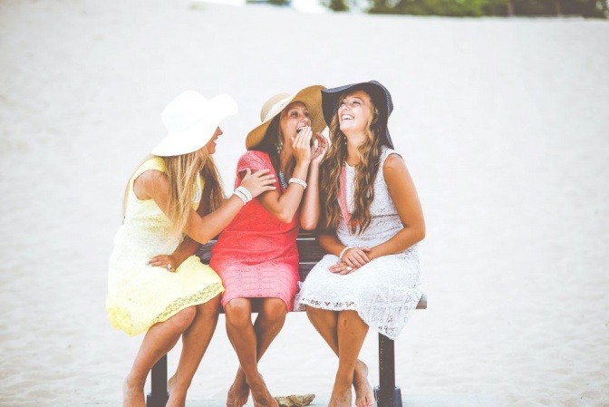 Drei Freundinnen sitzen in Stühlen und lachen miteinander