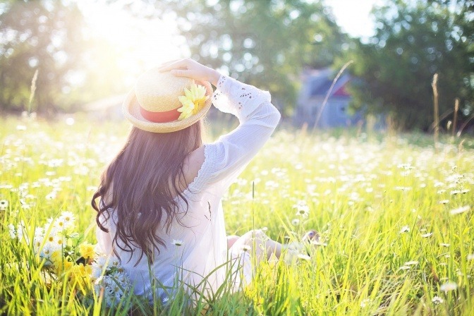 Frau sitzt im Gras und genießt die Frühlingssonne