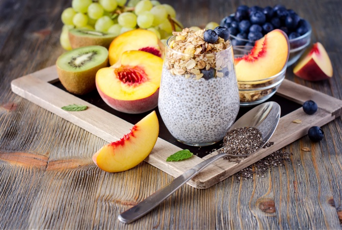 Ein gesundes Frühstück ist auf einem Tablett abgestellt. Darauf sind verschiedene Obstsorten und ein Müsli mit Chia-Samen zu sehen.
