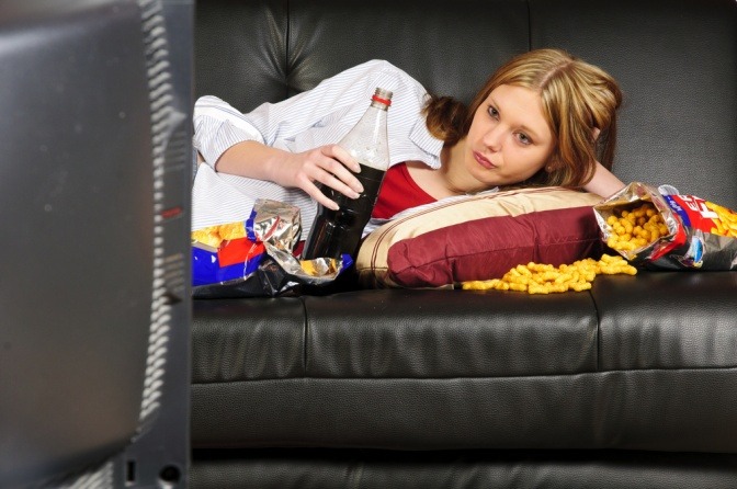 Frau zum Frust abbauen mit viel Junk-Food auf der Couch