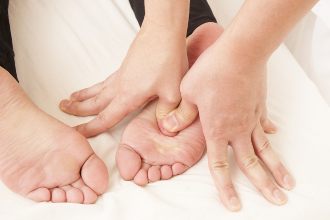 Mit den Finger wird Druck auf bestimmte Fußreflexzonen ausgeübt