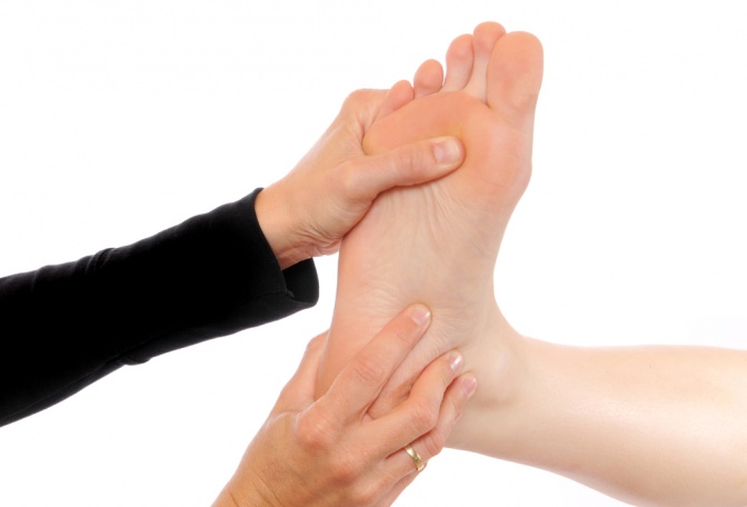 Eine Hand führt eine Fußreflexzonenmassage durch