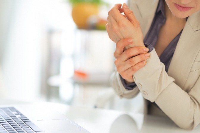 Eine Frau reibt sich den Arm vor Gelenksschmerzen