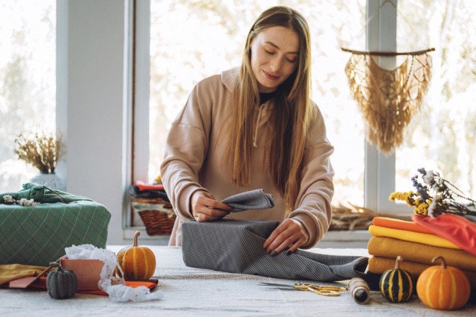 Junge Frau wickelt Geschenk in Furoshiki-Tuch ein.