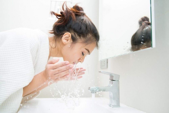 Eine Frau spült ihr Gesicht mit Wasser ab