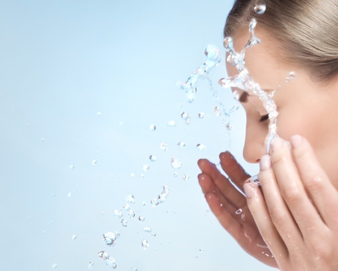 Eine Frau reinigt ihr Gesicht mit Wasser