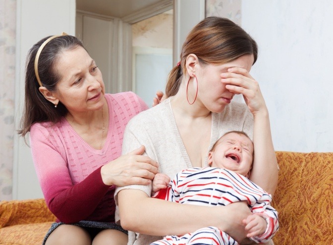 Eine Frau will mit einer weinenden Frau mit Baby sprechen