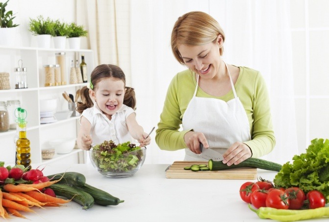 Frau kocht mit Kind gesunde Ernährung