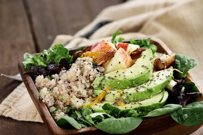 Eine Schüssel mit einem gemischten Salat, der unter anderem Quinoa, Avocado, und diverse Kräuter enthält.