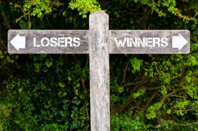 Auf Wegzeigern stehen die Worte Gewinner und Verlierer