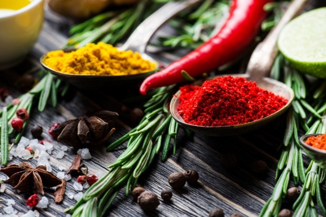 Eine Chilischote liegt neben Gewürzen