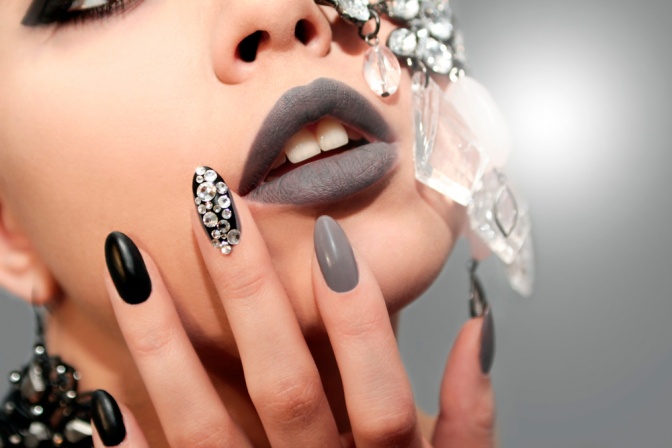 Eine Frau hält ihre Hände mit glamourösem Nageldesign ins Gesicht