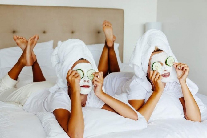 Zwei Frauen mit Gesichtsmasken und Gurkenscheiben auf den Augen