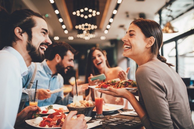 Vier Freunde essen in einem Restaurant und lachen dabei