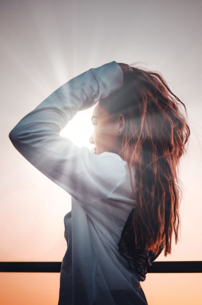 Eine Frau mit langen Haaren steht in der Sonne