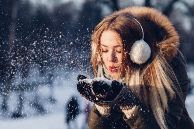 Frau im Winter hat ihre Haare mit Kapuze bedeckt