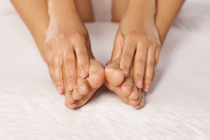 Hände umfassen Beine mit Lymphödem