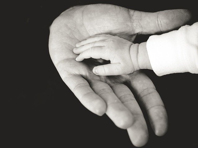 Eine Kinderhand liegt auf einer Erwachsenenhand