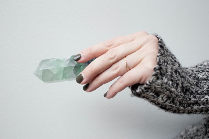 Eine Frau hält einen bläulich schimmernden Kristall in der Hand.
