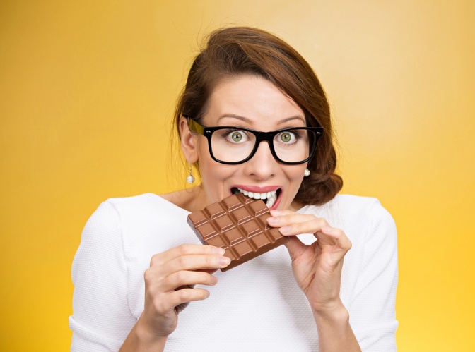Frau mit Heißhunger beißt in Schokoladentafel