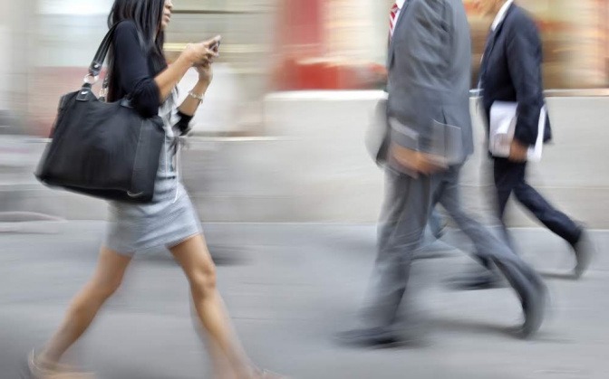 Eine Momentaufnahme einer belebten Fußgängerzone. Alles wirkt hektisch, die Menschen sind auf ihre Smartphones fixiert. 