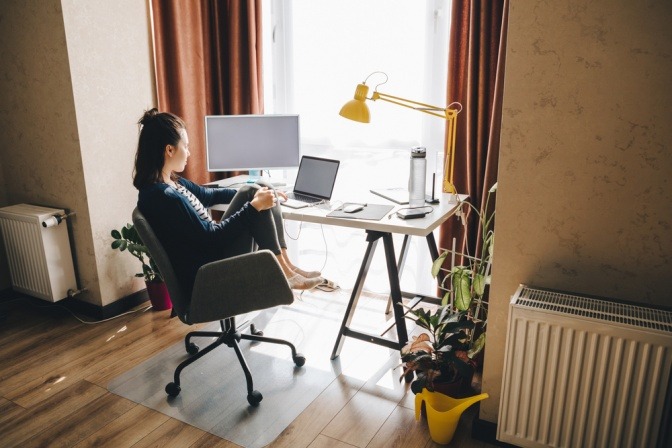 Homeoffice einrichten - eine Frau sitzt am Schreibtisch im heimischen Arbeitszimmer.