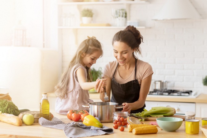 Frau kocht mit Mädchen gesunde Ernährung