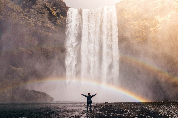 Ein Mann mit starkem Immunsystem steht vor einem Wasserfall