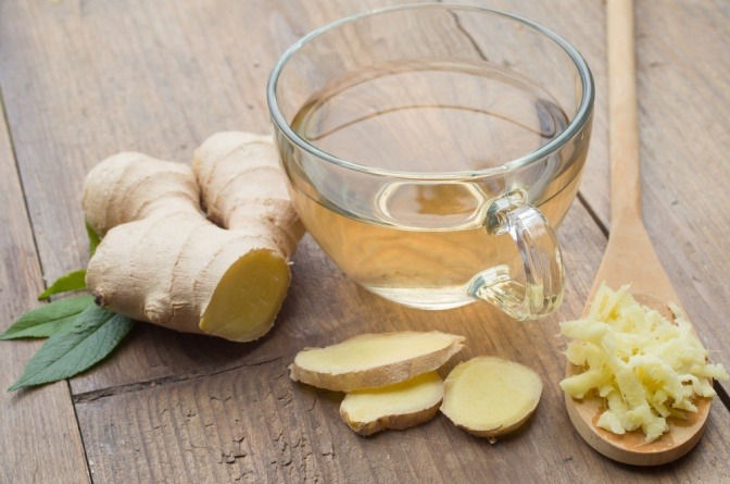 Eine Ingwerwurzel liegt neben einer Tasse Ingwerwasser