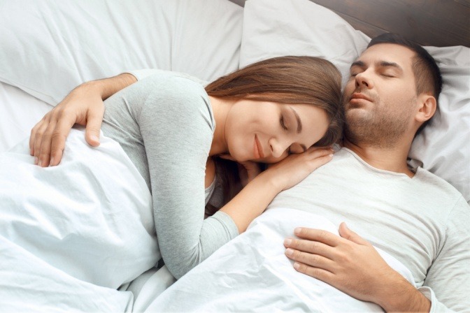Junges Paar schläft friedlich im Bett.