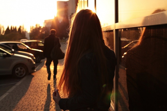 Frau blickt während des Sonnenuntergangs ihrem Partner hinterher, von dem sie sich gerade getrennt hat.