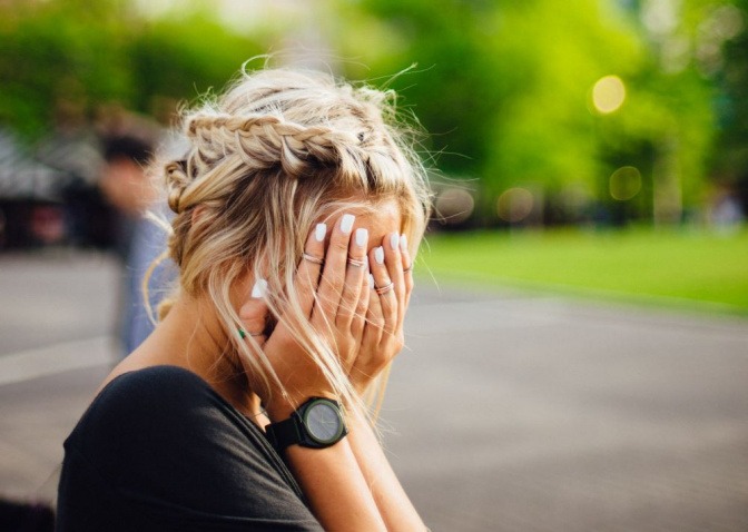 Eine Frau hält sich wegen Hautirritationen im Gesicht die Hände vor