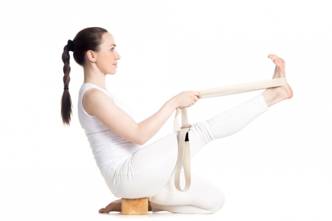 Eine Frau macht eine Übung für Iyengar Yoga mit einem Gurt