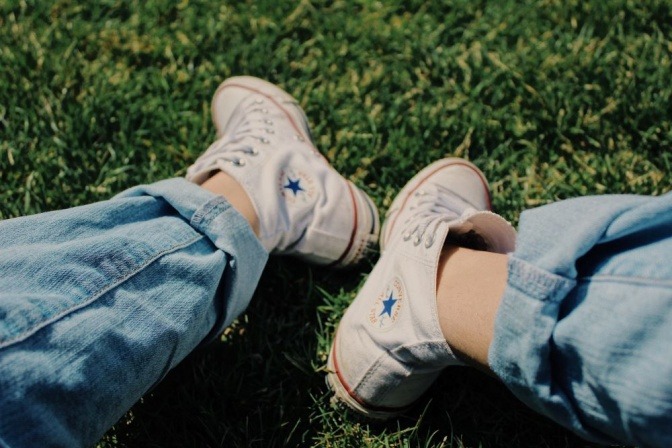 Eine Person trägt zu einer umgeschlagenen Jeans weiße Converse-Schuhe