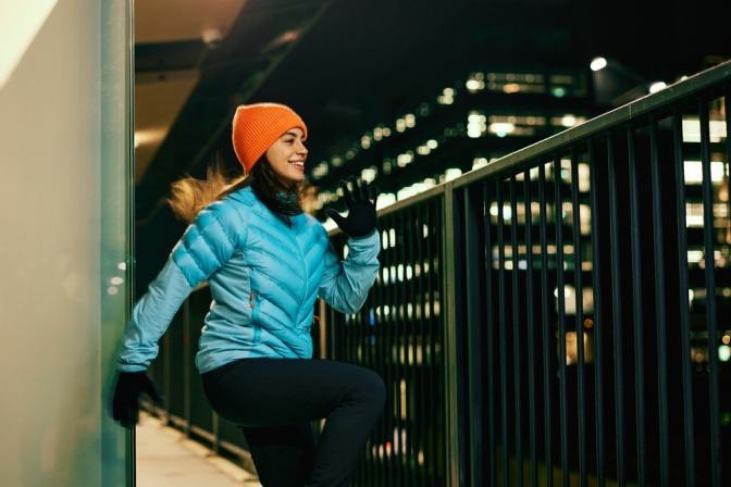 Frau beim Aufwärmen vor dem Joggen im Dunkeln