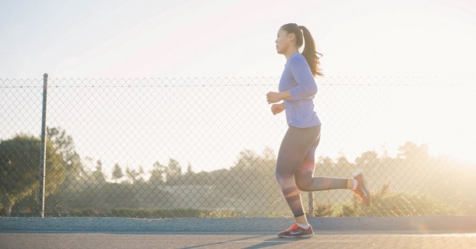 Eine Frau joggt mit dem Sonnenschein in ihrem Rücken