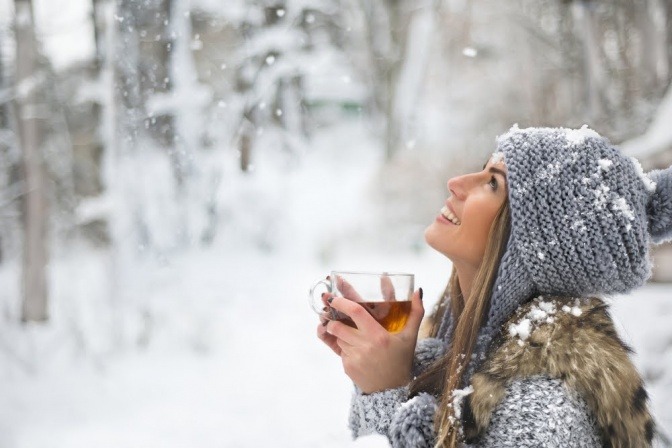 Eine Frau in der Kälte trinkt Tee