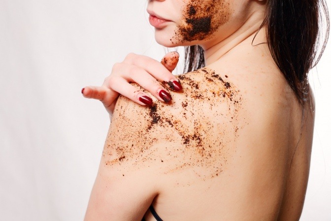 Eine Frau gibt Kaffee-Peeling auf ihre Haut