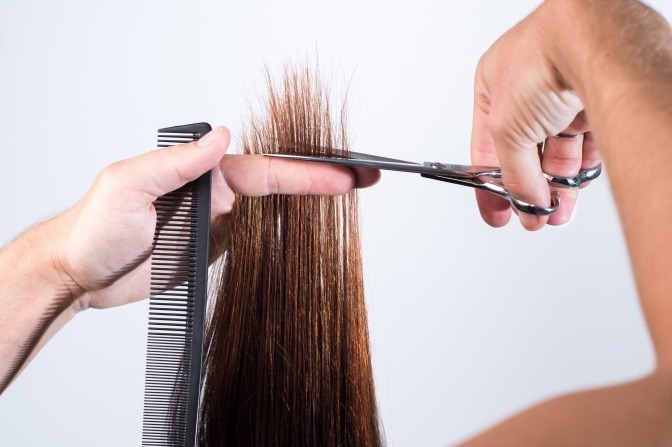 Eine Frau ist dabei, kaputte Haare zu reparieren mittels Spitzenschneiden