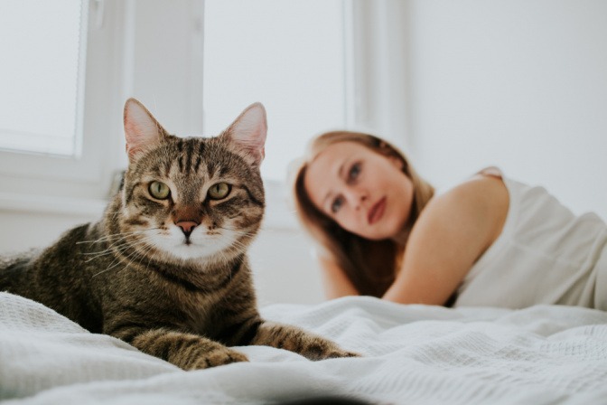 Eine Frau mit ihrer Katze im Bett.
