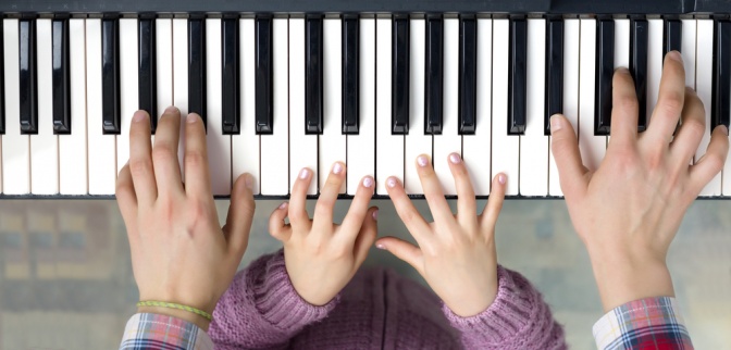 Klaviertasten mit zwei Händen die darauf spielen