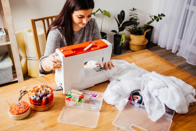 Frau arbeitet an einer Nähmaschine und macht Upcycling alter Kleidung.